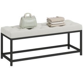 Banco pie de cama tapizado en terciopelo color crema con base de metal y diseño capitoné
